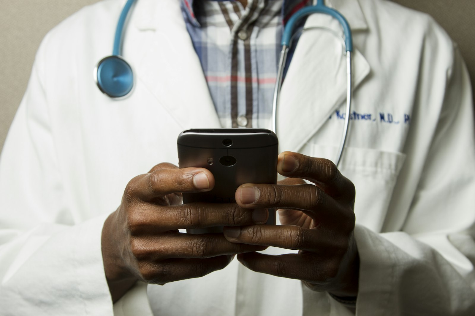 Clinician in a white coat using a phone to check the day's schedule